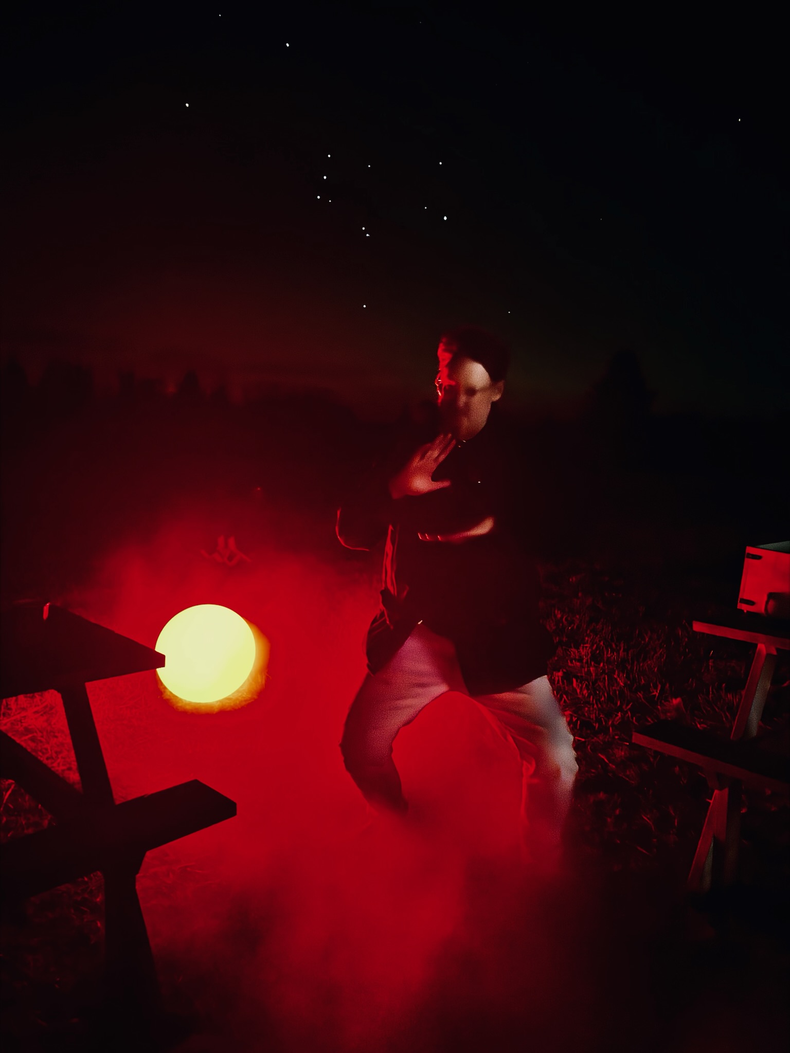 Scott dancing at night beneath the stars, lit by a red glow